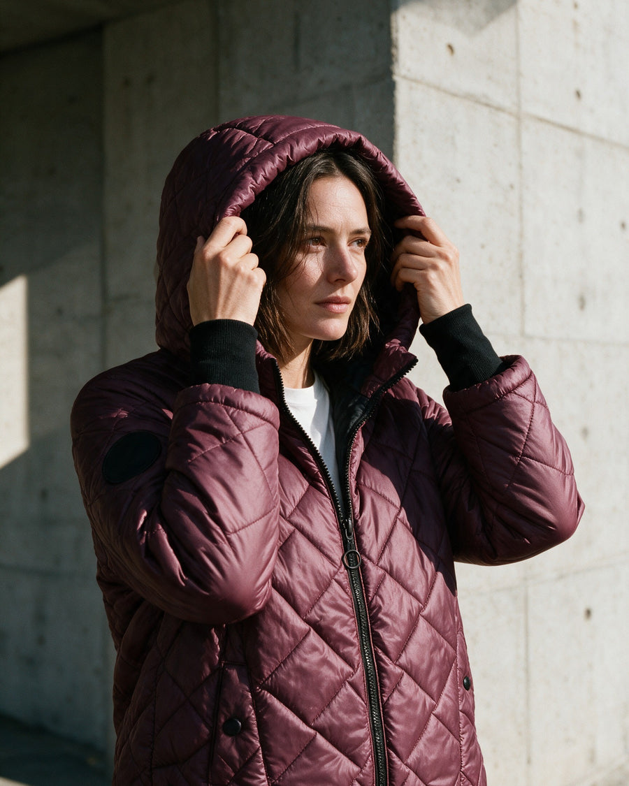 Woman in a burgundy quilted puffer with the hood up